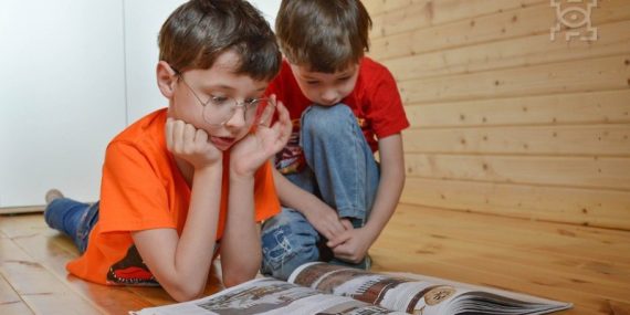 Dwaj chłopcy, w tym jeden w okularach czytający książkę, zdjęcie ilustracyjne